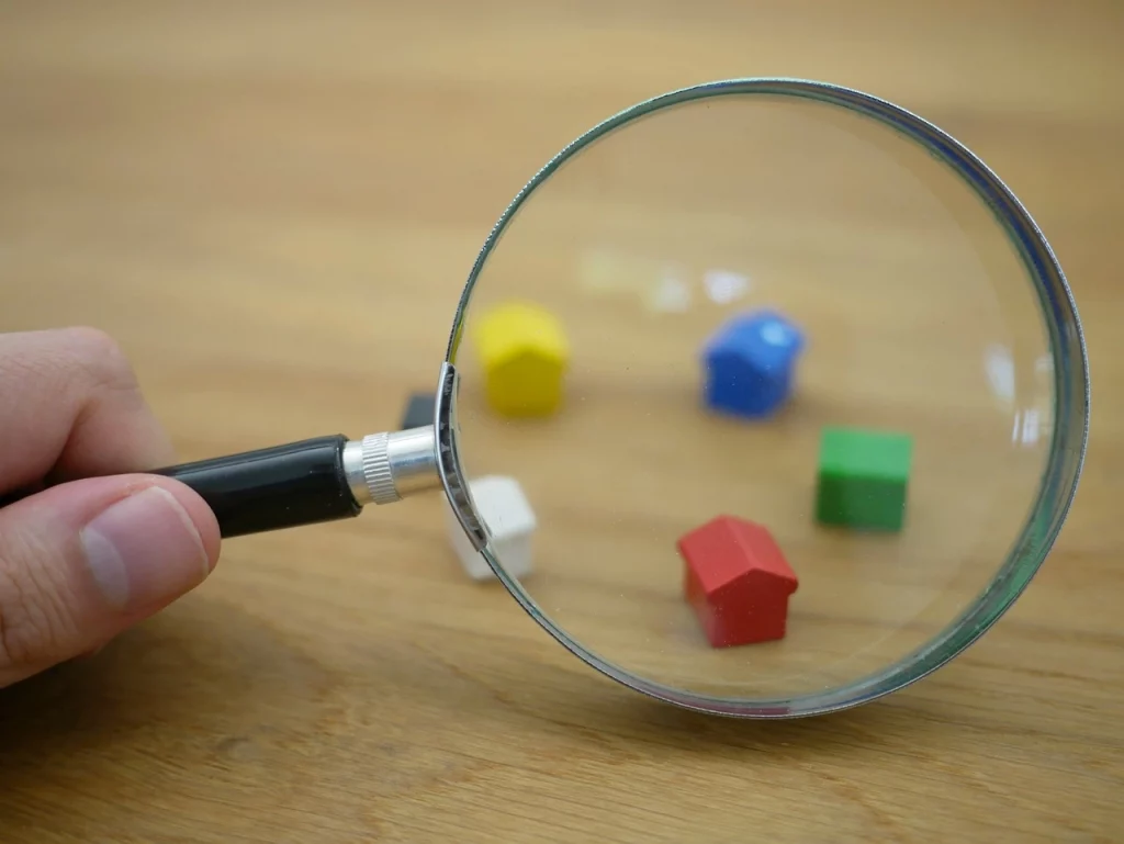 Das Bild zeigt eine Lupe mit der Miniaturen von Häusern vergrößert werden
